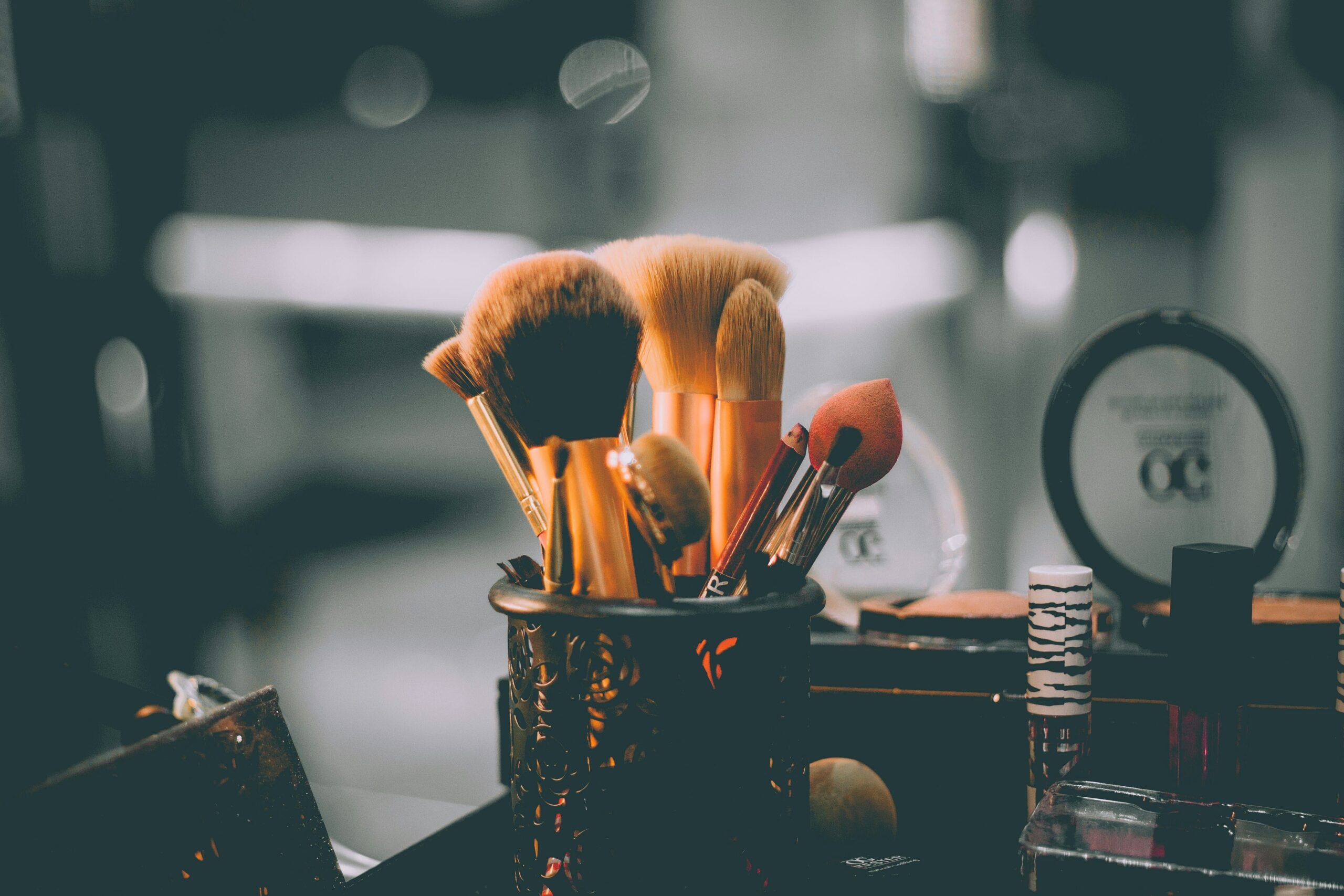 Close-up of makeup brushes and beauty products arranged neatly on a Glam-Haven Salon vanity, reflecting a professional and elegant makeup setup.